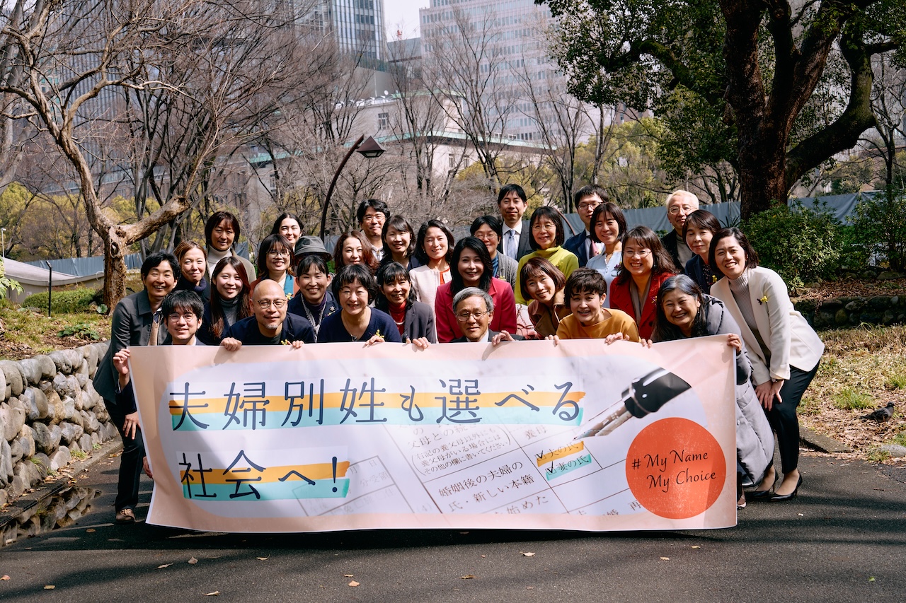東京訴訟の原告・弁護団の集合写真　横断幕を掲げている