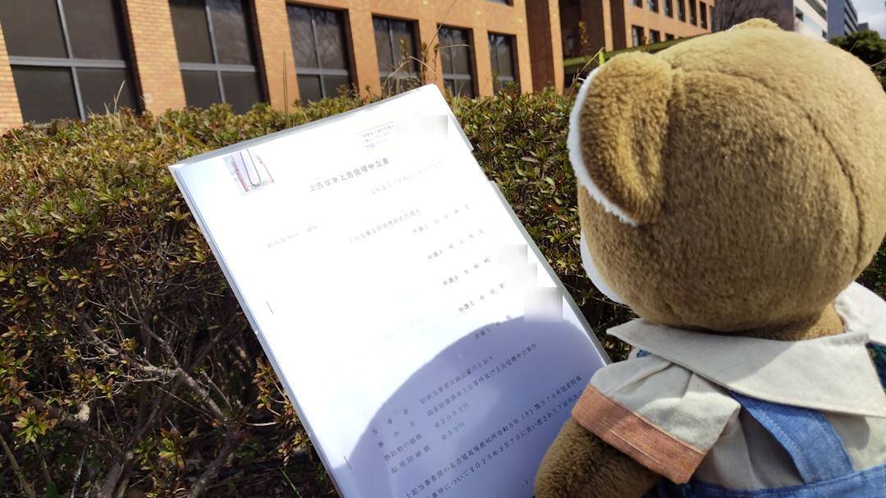 名古屋高裁の建物前で、くまちゃんが「上告状兼上告理由書」というタイトルの書類を持っている写真