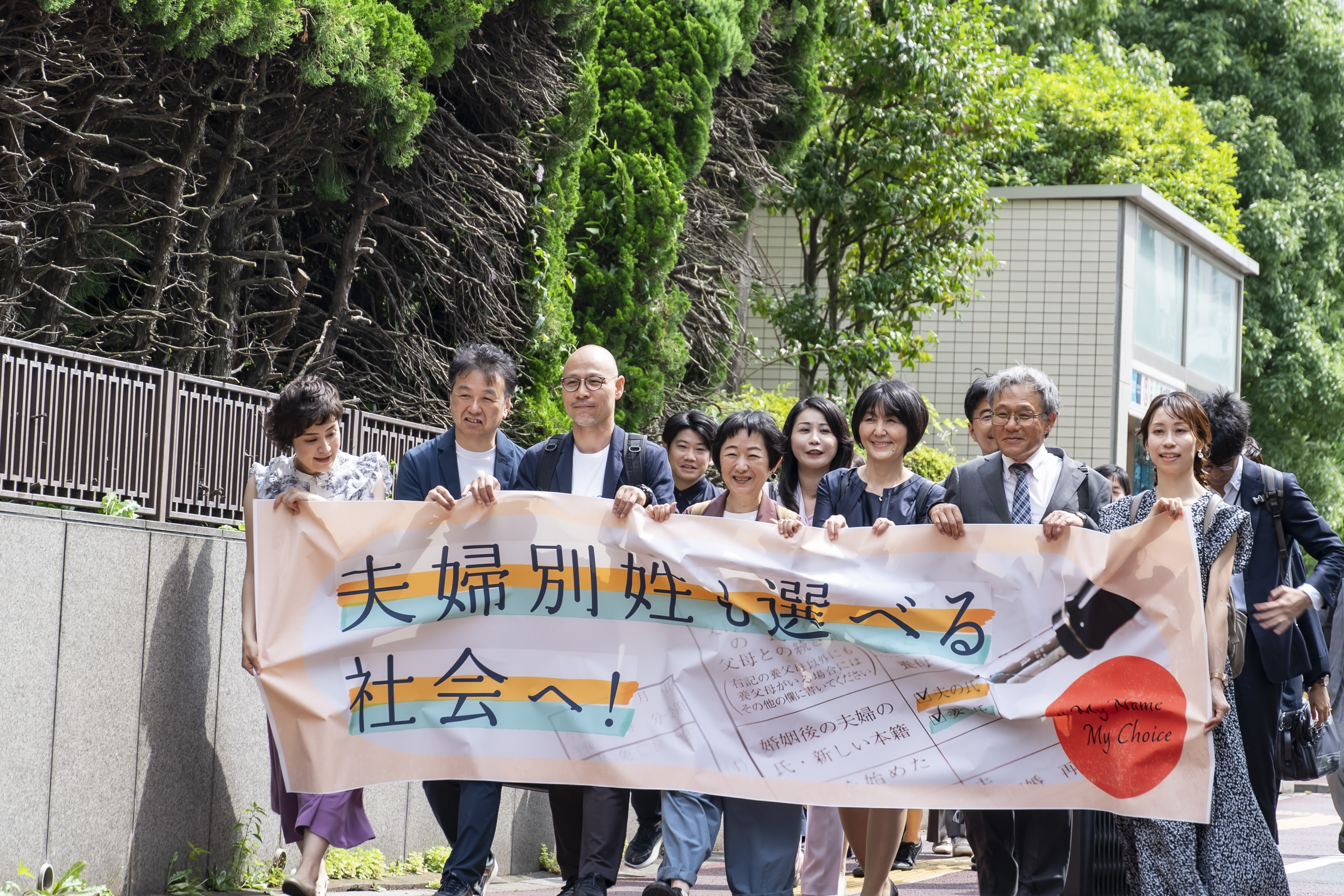 入廷行動の様子　「夫婦別姓も選べる社会へ」の横断幕と共に歩く原告の皆さん
