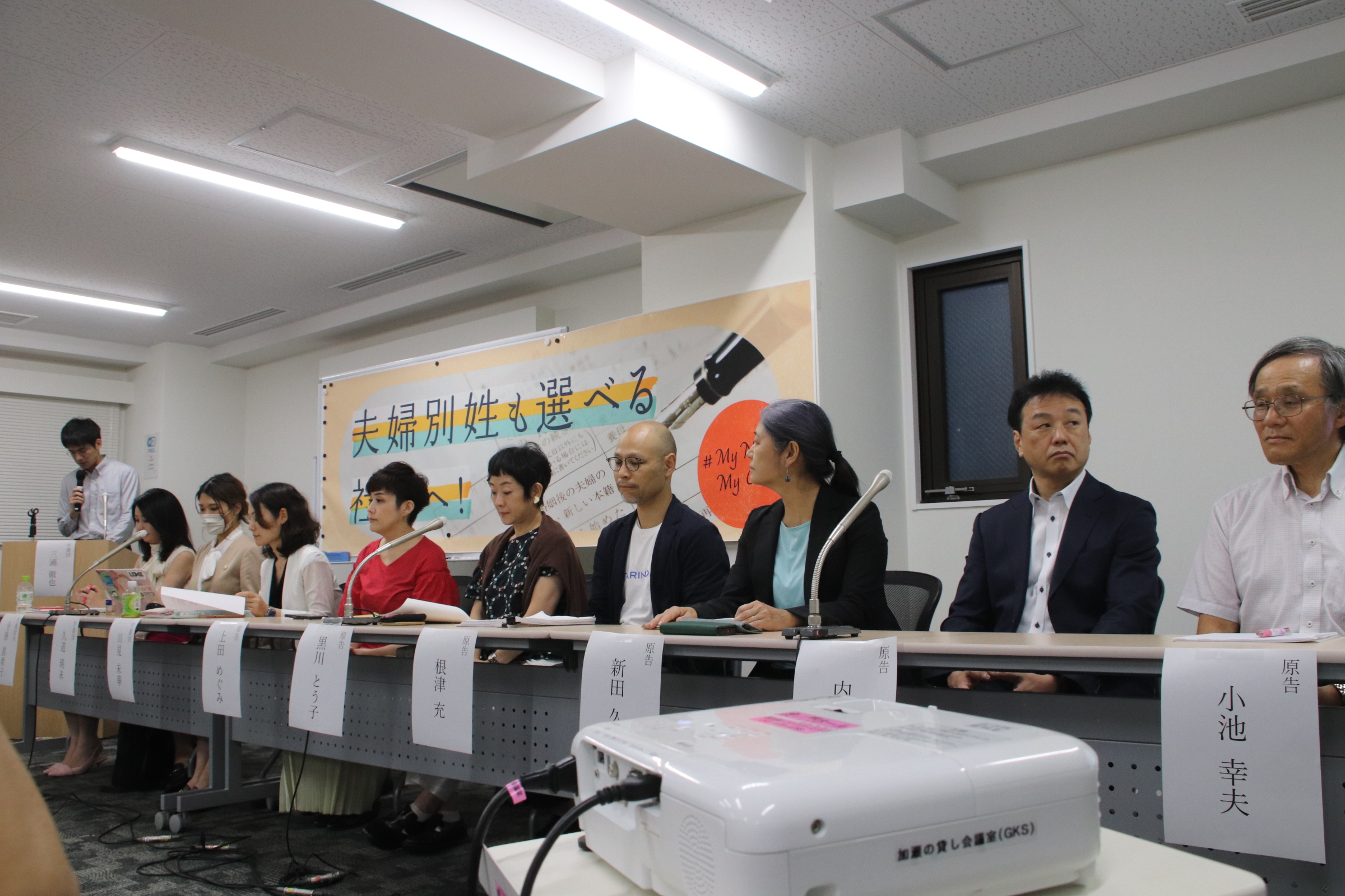 報告集会で弁護団と原告が長机に並んでいる様子