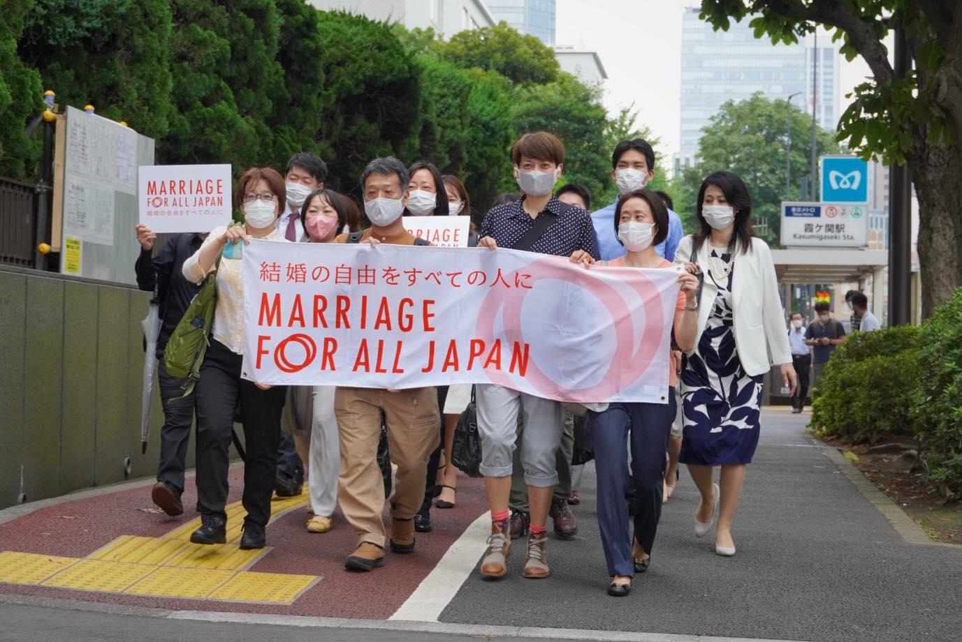東京地方裁判所に入るべく、数列になり歩く人々　１列目の人は、結婚の自由をすべての人にと書かれた横断幕を持っている