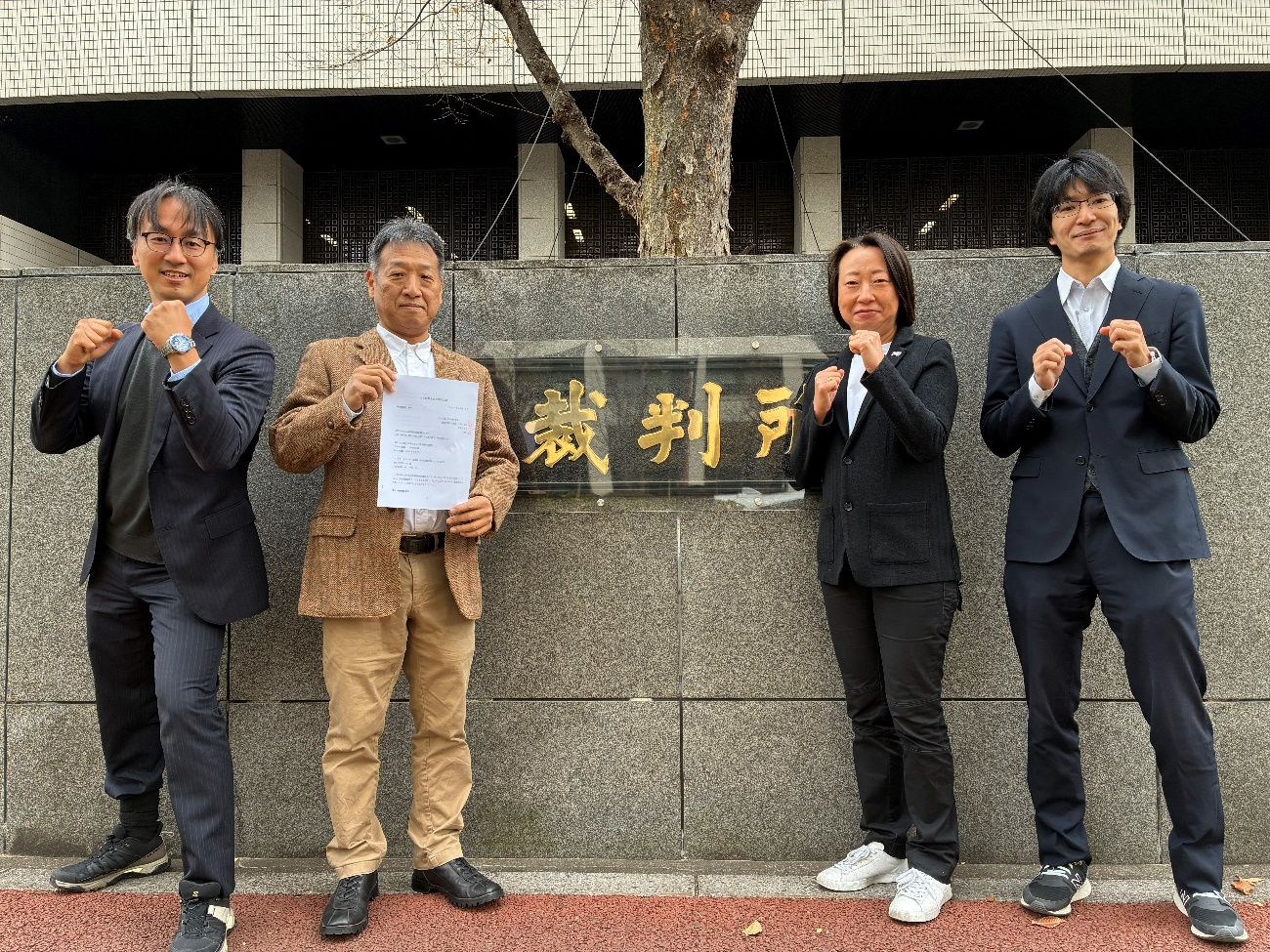 上告にあたって裁判所前でファイティングポーズをとる弁護団員と原告