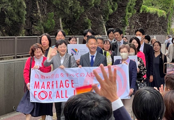 控訴審第２回口頭弁論期日の際、笑顔で「結婚の自由をすべての人に」「MARRIAGE FOR ALL JAPAN」と書かれた横断幕を掲げて東京地裁に向かう「結婚の自由をすべての人に」東京１次訴訟の原告と弁護団
