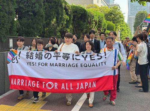 東京高等裁判所に入廷する「結婚の自由をすべての人に」東京２次訴訟の原告と代理人弁護士ら。沿道には駆けつけた支援者らがレインボーフラッグを持って応援の声をかけている。