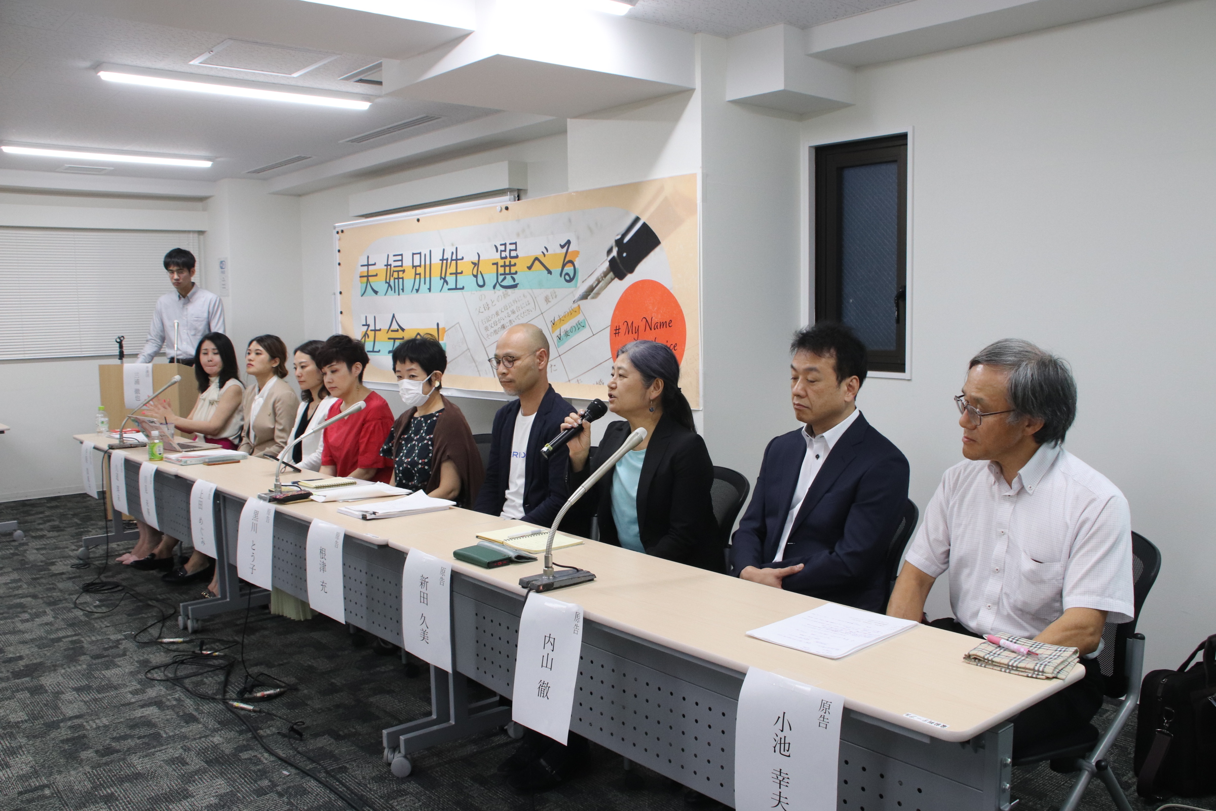 報告集会で弁護団と原告が長机に並んでいる様子